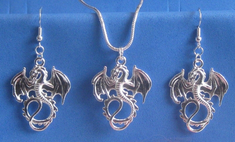 Op de afbeelding: Zilveren draken hanger ketting en oorbellen set. De draak staat met zijn vleugels uitgespreid.