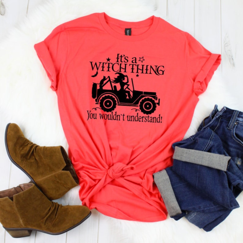 May include: A coral pink t-shirt with a black graphic of a witch driving a jeep. The text on the shirt reads "It's a Witch Thing. You wouldn't understand!"