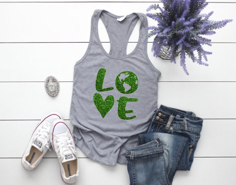 Puede incluir: Camiseta gris sin mangas con un gr&aacute;fico de purpurina verde que dice "LOVE" con un gr&aacute;fico de la Tierra de purpurina verde en lugar de la "O".
