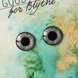 Pode incluir: Dois olhos de boneca cinzentos e pretos com um anel branco em torno da íris. Os olhos estão sobre um fundo de aquarela azul e verde.
