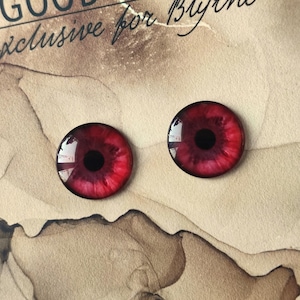 May include: Two red glass eyes with black pupils. The eyes have a dark red rim and a light red centre.