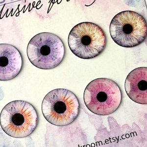 Può includere: Set di 7 occhi di vetro colorati con pupille nere. Gli occhi sono di varie tonalità di rosa, viola e arancio. Gli occhi sono disposti a semicerchio su uno sfondo bianco con il testo "kroom.etsy.com" e "E1-03" nell'angolo.