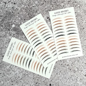Puede incluir: Tres tarjetas de pegatinas de transferencia de cejas en varios tonos de marrón y negro. Cada tarjeta lleva la etiqueta "GOOD BROWS" y "Transfer stickers for full custom." También se ve el sitio web goodworkroom.etsy.com.
