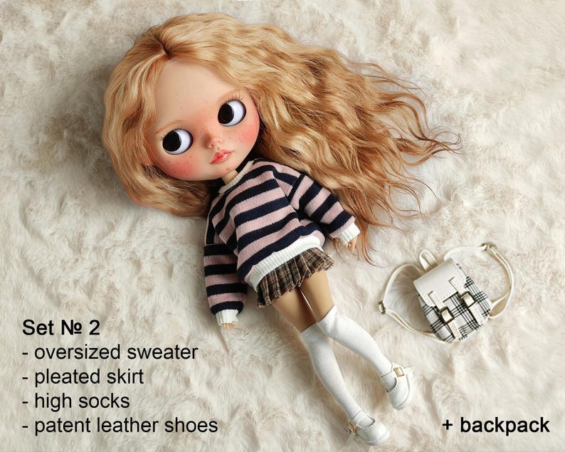 Op de afbeelding: Een pop met lang blond haar die een gestreepte trui, een geplooide rok, hoge sokken en lakschoenen draagt. De pop houdt een kleine wit-zwarte geruite rugzak vast.