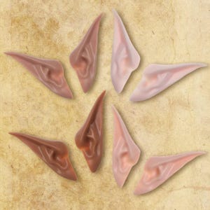 May include: Six pairs of elf ears in different shades of brown and pink. The ears are made of a soft, flexible material and are designed to be worn as a costume accessory.
