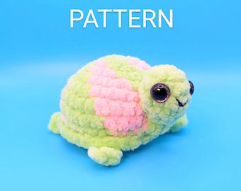 May include: A crocheted green and pink turtle toy with black eyes. The toy is on a blue background.