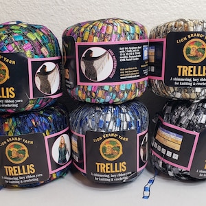 Pode incluir: Seis novelos de fio Lion Brand Trellis em várias cores, incluindo azul, verde, dourado e prata. O fio é um fio de fita lacy brilhante para tricô e crochê.