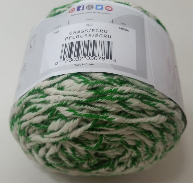 May include: A ball of green and white yarn with the label "GRASS/ECRU PELOUSE/&Eacute;CRU" and the color number 203. The label also includes a barcode and the text "Made in China".
