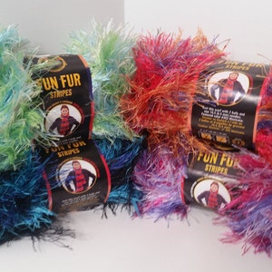 May include: Four skeins of Fun Fur Stripes yarn in various colors, including teal, green, orange, and purple. Each skein has a label with the brand name and the words "Fun Fur Stripes".