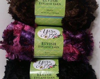 May include: Three skeins of Yarn Bee Elvish Eyelash yarn. The skeins are in the colors Mocha, Raisin, and Licorice. Each skein is 3.5 ounces and 118 yards.