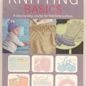 May include: A book titled "Knitting Basics" with a purple cover. The cover features images of knitted items, including a baby in a knitted hat, a blanket, and a pair of gloves. The book is a step-by-step course for first-time knitters.