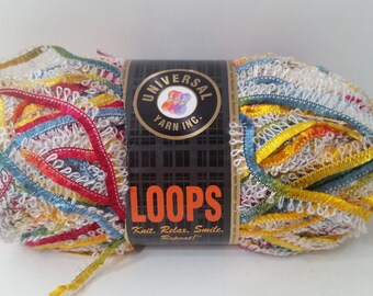 May include: A skein of colourful yarn called "Loops" by Universal Yarn Inc. The yarn is a mix of white, yellow, red, blue, and green ribbon-like strands. The label says "Knit. Relax. Smile. Repeat!"