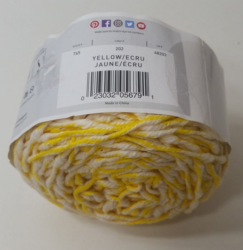 May include: A ball of yellow and ecru yarn with a label that reads "YELLOW/ECRU JAUNE/&Eacute;CRU" and has the barcode 23032 05679. The label also states "Made in China".