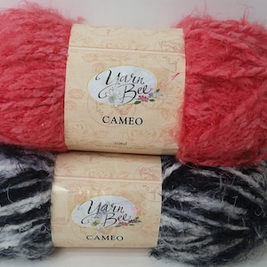 Könnte beinhalten: Zwei Knäuel Yarn Bee Cameo Garn. Ein Knäuel ist korallenrosa und das andere ist schwarz-weiß.