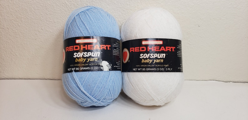 Puede incluir: Dos ovillos de hilo para bebé Red Heart Sofspun, uno en azul claro y otro en blanco. Cada ovillo pesa 85 gramos (3 oz) y es de 3 cabos.