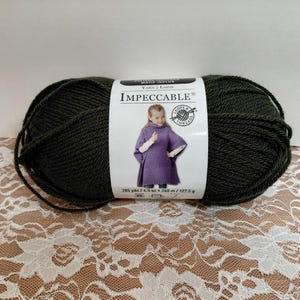 May include: A large ball of dark green yarn with a label that reads "Impeccable". The label features a girl wearing a purple poncho. The yarn weighs 4.5 oz / 127.5 g and is 795 yds / 727 m.