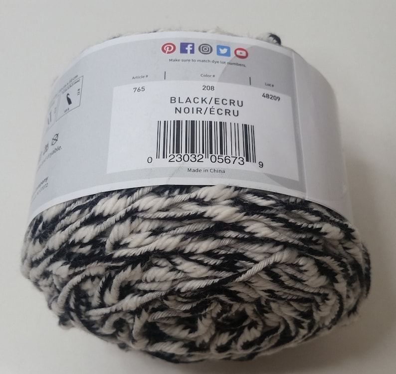 May include: A ball of black and ecru yarn with a label that reads "Black/Ecru Noir/Ecru" and has a barcode and the number 208. The label also says "Made in China".