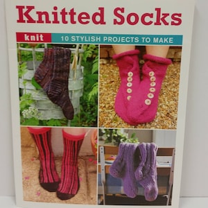 Puede incluir: Portada del libro "Knitted Socks" con el subtítulo "10 Stylish Projects to Make". La portada presenta imágenes de calcetines de punto en varios colores y estilos, incluyendo un par de calcetines rosas con botones.