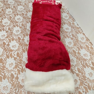 May include: A red plush Christmas tree skirt with a white faux fur trim. The packaging reads "42" Plush Tree Skirt". The skirt is folded and ready for use, adding a festive touch to holiday decor.