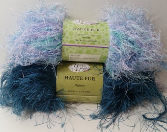 May include: Two skeins of yarn in blue and purple shades. The yarn is called "Haute Fur" and is made by "Yarn & Bree".
