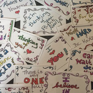 May include: A collection of colorful handwritten cards with encouraging messages, such as "You are Awesome!" and "I believe in you!" The cards are decorated with swirls and hearts.