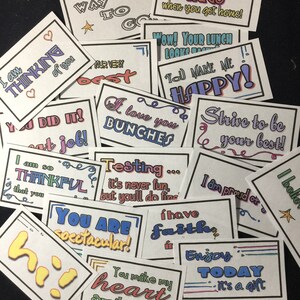 Może przedstawiać: Zbiór kolorowych, ręcznie napisanych kartek z pozytywnymi wiadomościami. Kartki charakteryzują się różnymi czcionkami, kolorami i wzorami, w tym sercami, gwiazdami i ozdobnymi zawijasami. Niektóre z wiadomości to: "You did it!", "I am so thankful", "You are spectacular!", "I love you bunches", "Testing... it's never fun, but you'll do fine", "I have faith", "Enjoy today - it's a gift", and "Strive to be your best!"