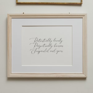 May include: A white framed print with black calligraphy that reads "Potentially lovely, Perpetually known, Suspended and open".