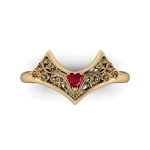 May include: A gold ring with a delicate filigree design and a red heart-shaped gemstone in the center.