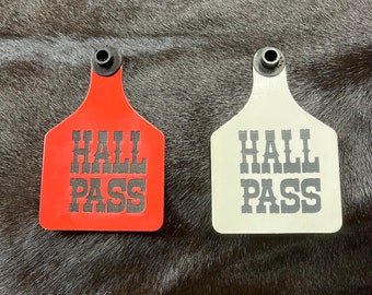 Op de afbeelding: Twee rode en witte plastic kaartjes met de tekst "Hall Pass" in zwarte letters.