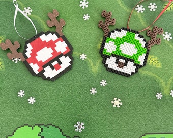 May include: Two pixel art Christmas ornaments, one red and white mushroom with brown antlers and one green and white mushroom with brown antlers.