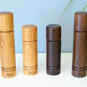 Può includere: Quattro macinini per sale e pepe in legno con finitura in legno naturale. I macinini sono tutti della stessa dimensione e forma, ma sono realizzati in diversi tipi di legno. I macinini sono etichettati "Art of the Wood".