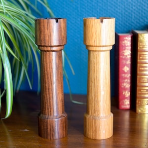 Könnte beinhalten: Zwei Schachfiguren aus Holz, ein dunkler brauner Turm und ein heller brauner Turm, stehen auf einer Holzoberfläche. Die Türme sind mit komplizierten Details geschnitzt und haben ein klassisches Design.