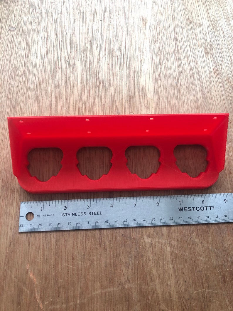 May include: A red plastic shelf with four round cutouts. The shelf is 20 cm long and has a ruler underneath it.