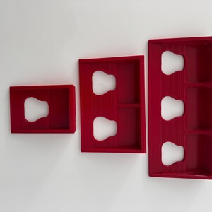 May include: Three red plastic organisers with different sized compartments. Each compartment has a rounded cutout.