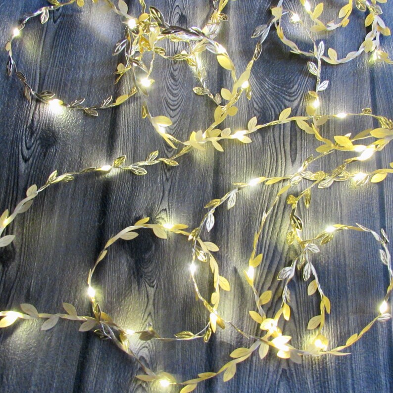 May include: Gold leaf garland with warm white LED lights. The garland is made of artificial leaves and is perfect for decorating for a wedding, party, or holiday.