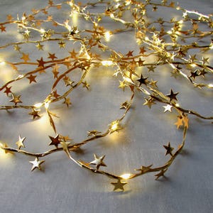 May include: Gold string lights with star-shaped cutouts. The lights are strung on a clear wire and are perfect for adding a touch of sparkle to any room.