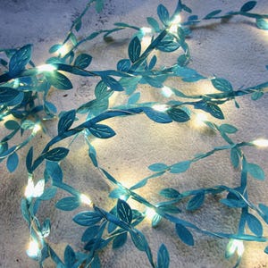 May include: A string of teal blue fairy lights with leaves, perfect for adding a touch of whimsy to any space.