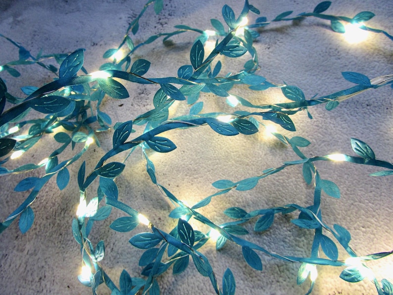 May include: A string of teal blue fairy lights with leaves, perfect for adding a touch of whimsy to any space.