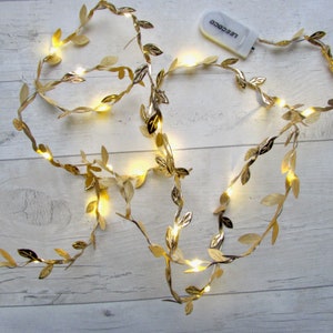 May include: Gold leaf garland with warm white LED lights. The garland is battery operated and has a small remote control.