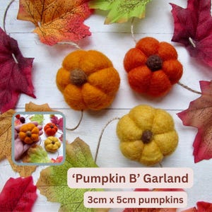 May include: A garland featuring three felted pumpkins in orange, bright orange, and yellow, each with a brown stem. The pumpkins measure 3cm by 5cm. The garland is decorated with artificial autumn leaves in red, orange, and green shades.