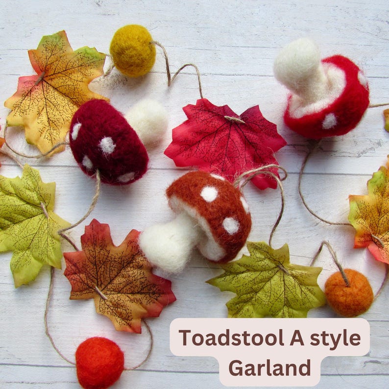 May include: A garland featuring felted toadstools in red and brown with white spots, interspersed with artificial autumn leaves in yellow, orange, and red, and small felted balls. The text Toadstool A style Garland is visible.