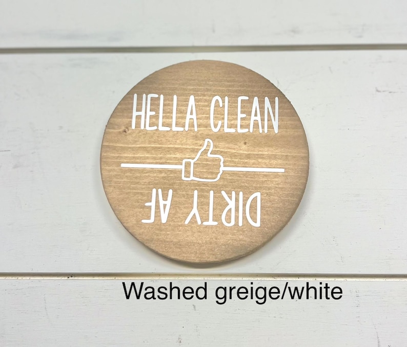 Pode incluir: Uma placa redonda de madeira com as palavras "HELLA CLEAN" acima de um s&iacute;mbolo de polegar para cima e as palavras "DIRTY AF" abaixo. A placa &eacute; marrom claro com letras brancas e uma linha horizontal branca.