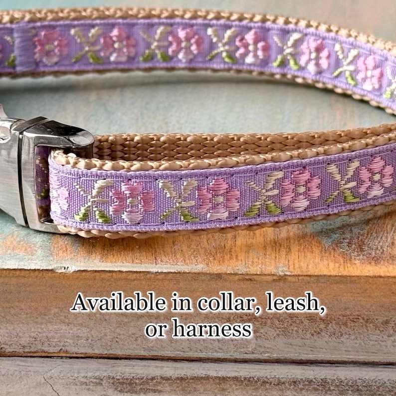 Puede incluir: Un collar de perro marr&oacute;n claro con una cinta morada con un patr&oacute;n floral. La cinta tiene acentos rosados y verdes. El collar est&aacute; disponible en collar, correa o arn&eacute;s.