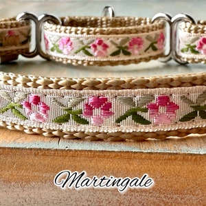 May include: A beige dog collar with a pink and green floral pattern. The collar is a martingale style, with a metal loop on one side.
