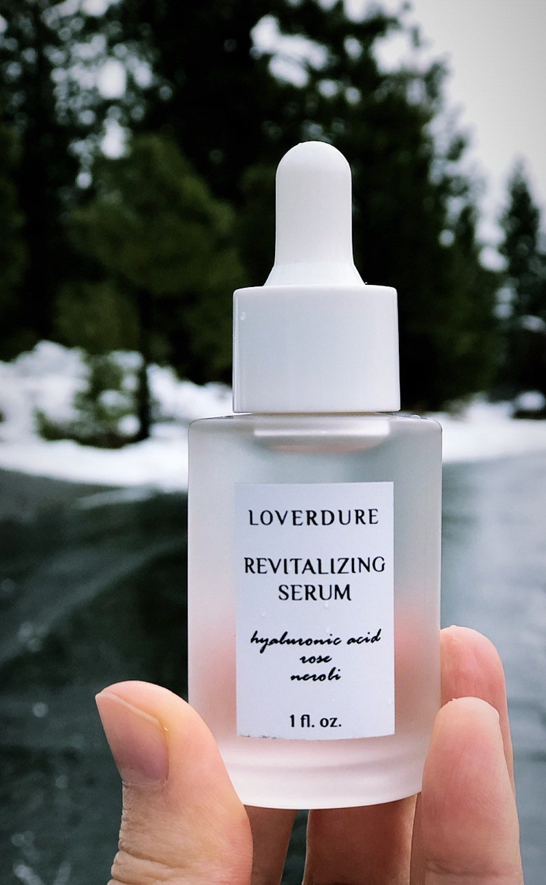 May include: A clear glass bottle with a white dropper top and label. The label reads "LOVERDURE REVITALIZING SERUM hyaluronic acid rose neroli 1 fl. oz."