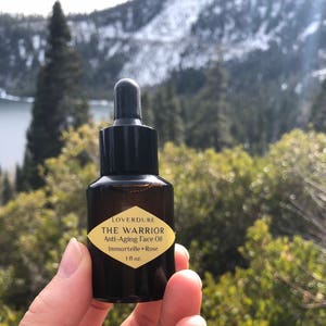 May include: A brown glass bottle with a dropper top, labeled "LOVERDURE THE WARRIOR Anti-Aging Face Oil Immortelle+Rose 1 fl oz."