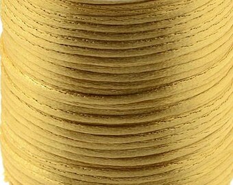 May include: A spool of gold-colored waxed cord, wound tightly on a white plastic bobbin.