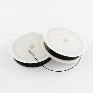 May include: Two spools of black wire, each wound around a white plastic spool.