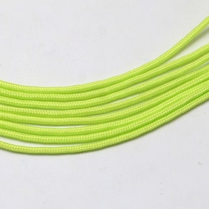 Könnte beinhalten: Nahaufnahme eines Bündels neon-grüner Paracord. Das Paracord ist fächerförmig angeordnet, wobei sich die Enden der Schnüre überlappen.