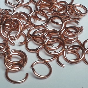 Puede incluir: Un montón de pequeños anillos de salto de color cobre. Los anillos son todos del mismo tamaño y están dispuestos en un patrón aleatorio.